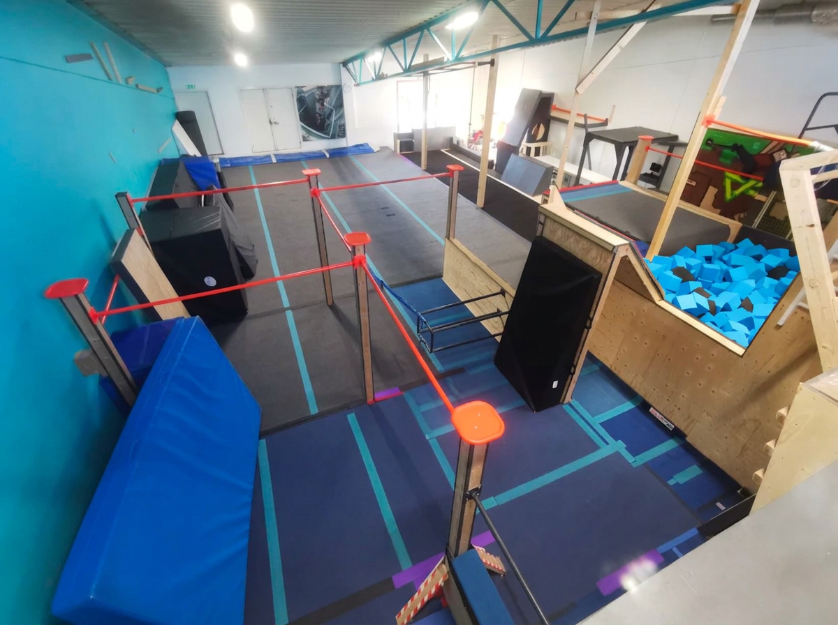 Parkourhallen i Partille med hinder, mattor och blå foampit